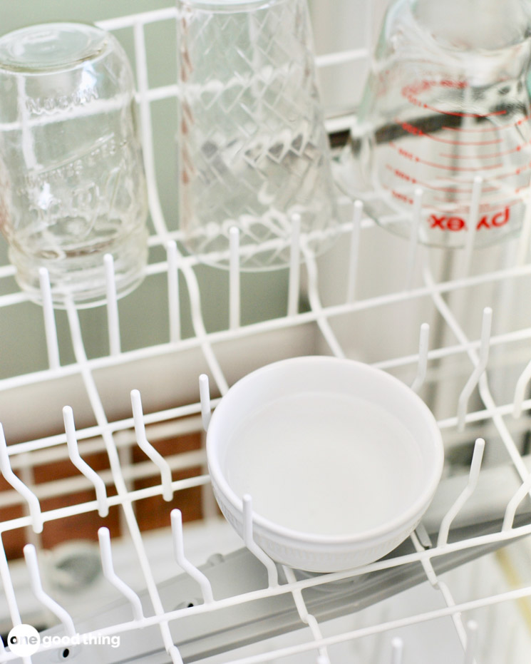 A dish of vinegar in the top rack of a dishwasher