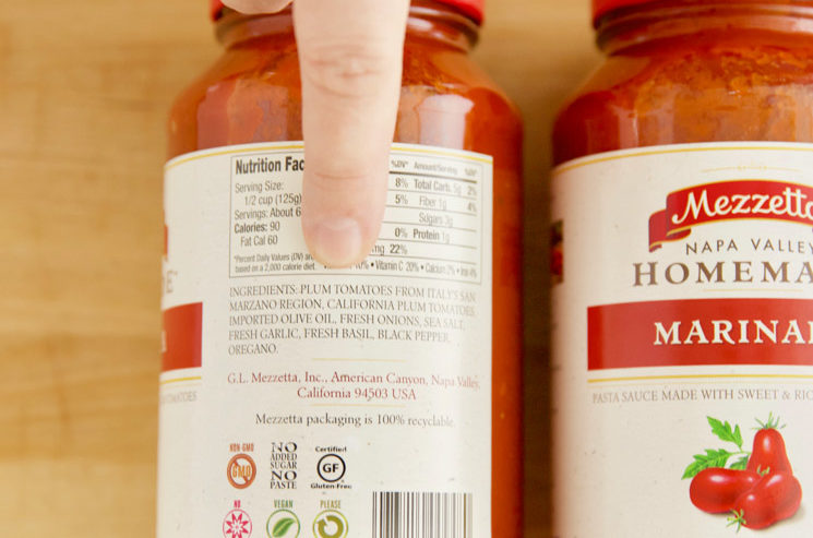 Photo of finger showing that the first ingredient in a jar of pasta sauce is tomatoes.