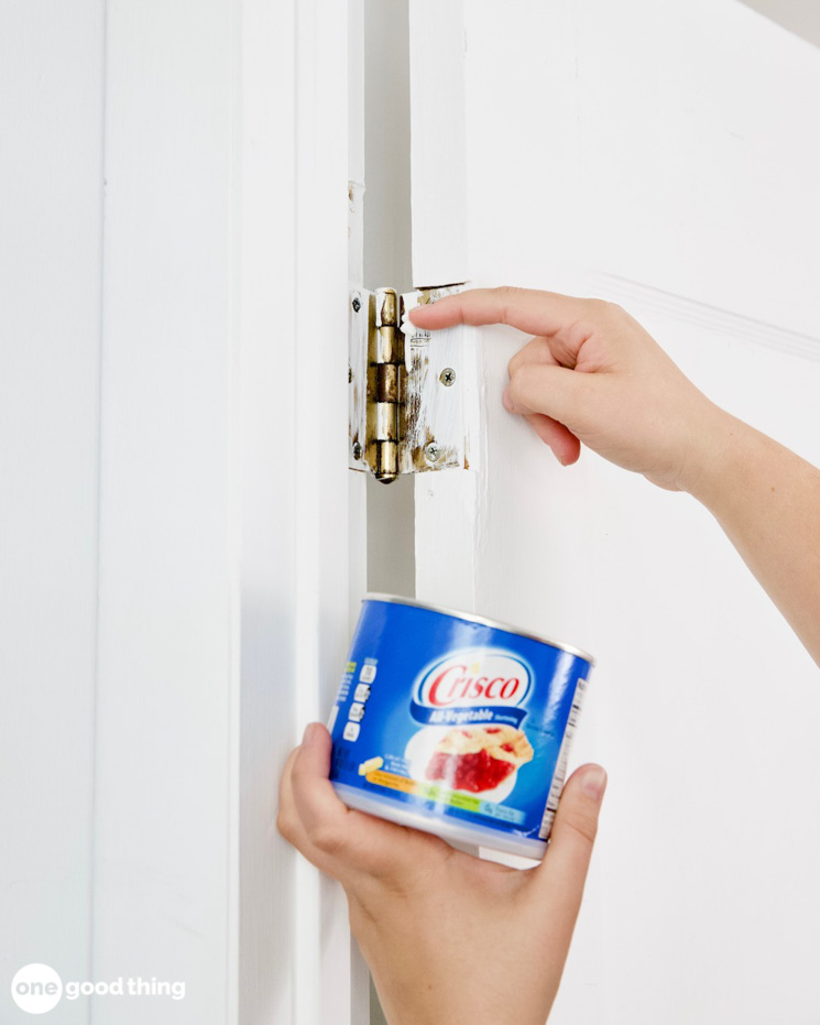 A person opening a can of cola on a door.