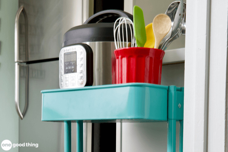 A pot, pans and utensils are on an IKEA cart in a kitchen.