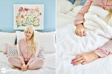 A woman wearing pajamas sits on a bed.