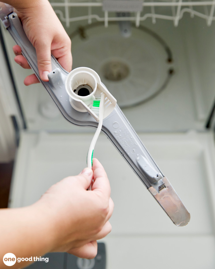 Clean the dishwasher spray arms by removing them first, then use a soft brush.