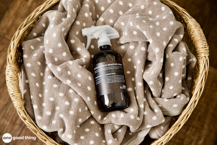 Solving Laundry Problems - spray bottle of homemade stain remover on top of laundry in a basket