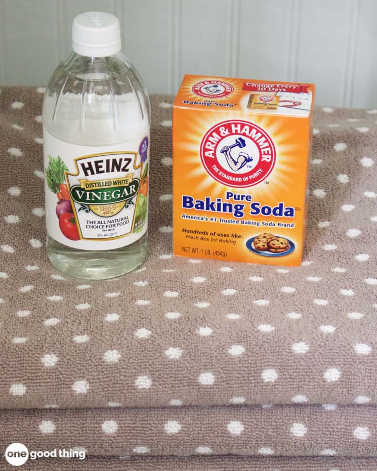 Solving Laundry Problems - stack of towels with bottle of white vinegar and box of baking soda