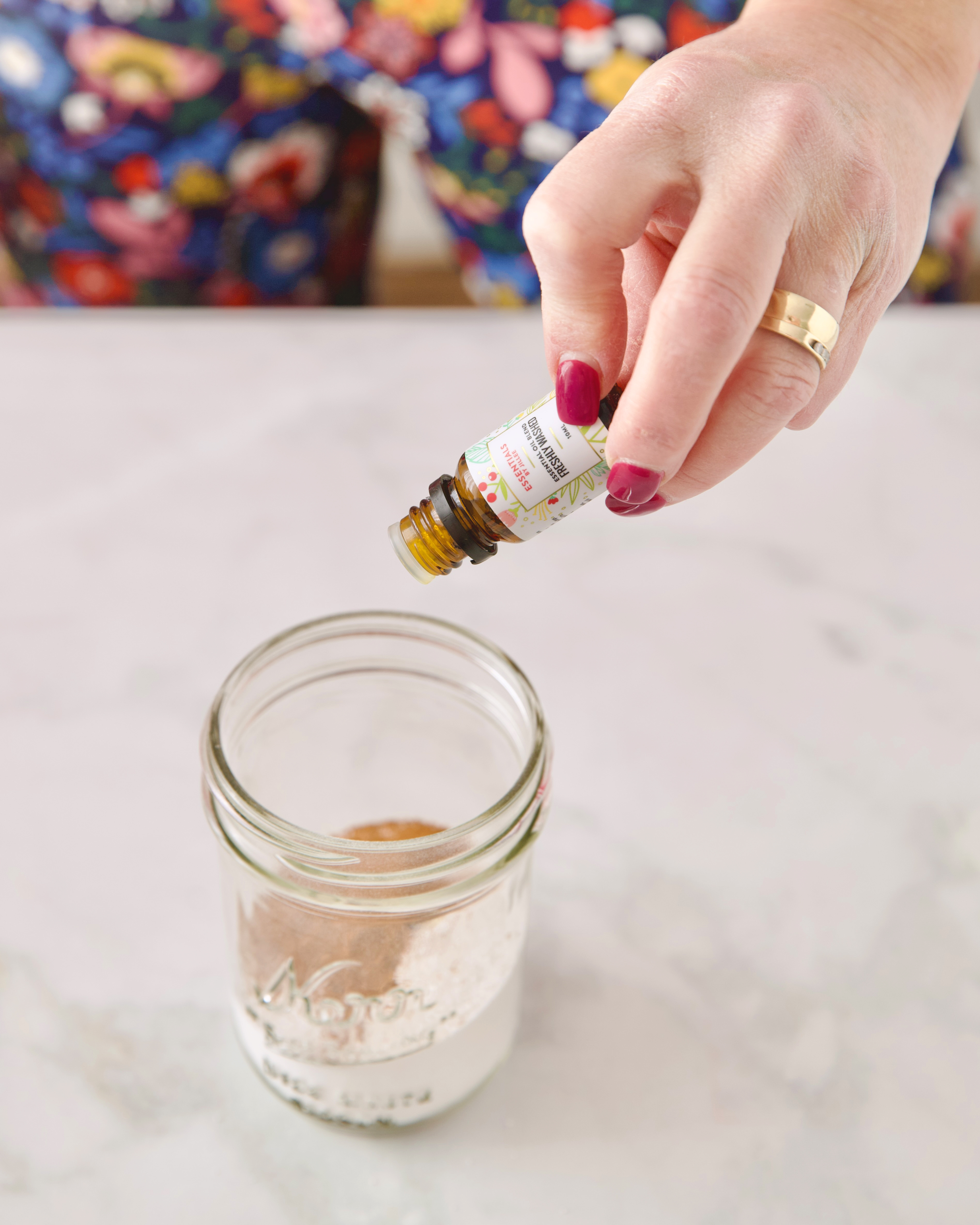 woman's hand putting essential oil into powder in a jar