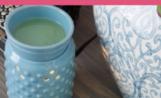 An image of a blue ceramic wax melter beside white wax melts in a glass container. The background includes part of a decorative ceramic piece. Text at the top reads, "How to make your house smell good.