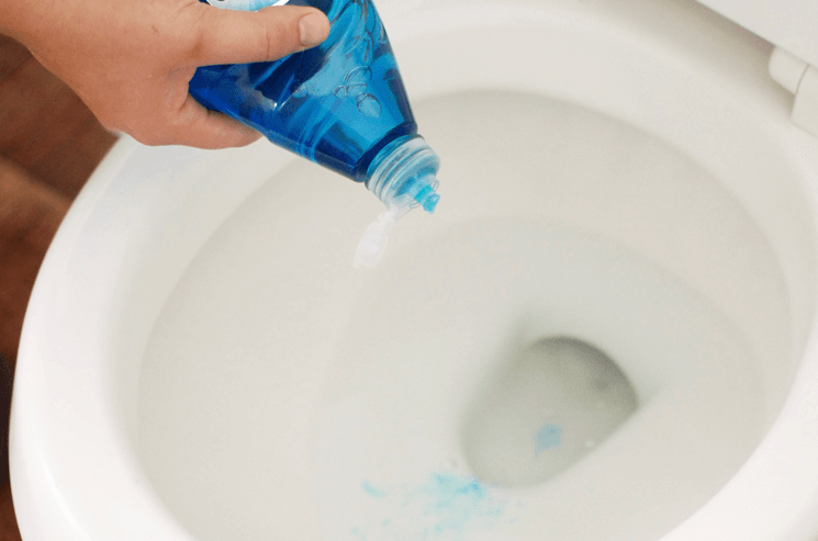 squirting blue dawn dish soap into a toilet 