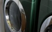 Two green washing machines in a room.